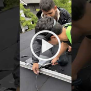 Two men work on a car roof, installing a sunroof or roof rack with wires and tools visible. (Video thumbnail)