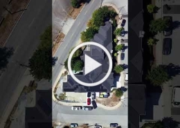 Aerial view of a suburban cul-de-sac with cars; play button overlay indicates video thumbnail.