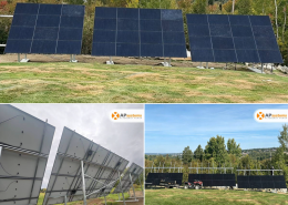 Three solar panels on metal frames in a grassy field with trees in the background.